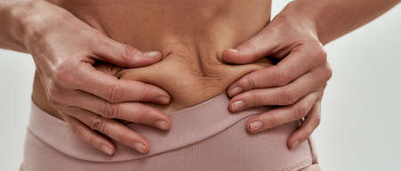 Slim middle aged caucasian woman squeezing flabby skinの写真素材