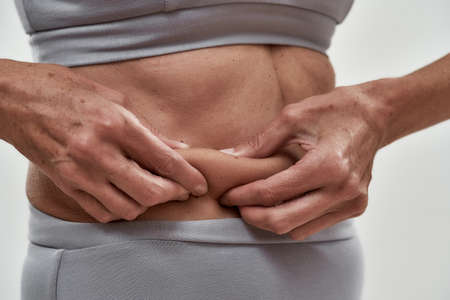 Slim middle aged woman showing folded skin on waistline