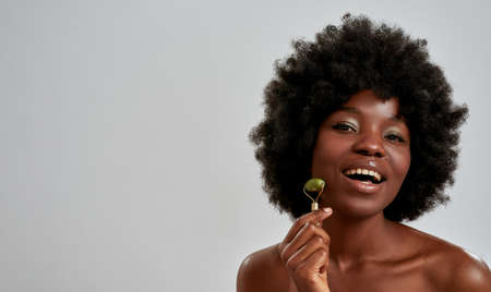 Portrait of excited young african american woman with perfect glowing skin smiling at camera while...