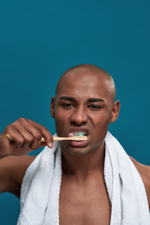Discontent adult man moving toothbrush up and down in mouth