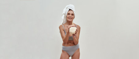 Happy middle aged woman drinking smoothie from coconutの写真素材