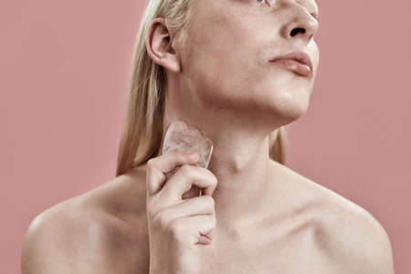 Young caucasian guy using quartz tool for neck massageの写真素材