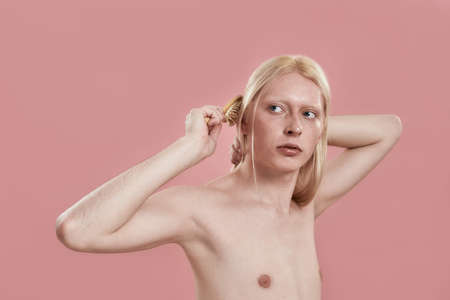 Young caucasian man combing his long blond hairの写真素材