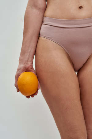 Hand carrying an orange near a hipの写真素材