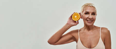 Blonde female with short hair lifting orange to earの写真素材
