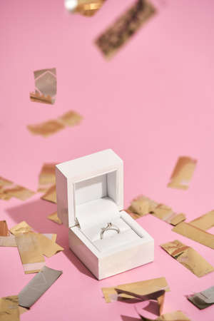 Romantic present for her. Vertical shot of elegant engagement diamond ring in white gift box and...