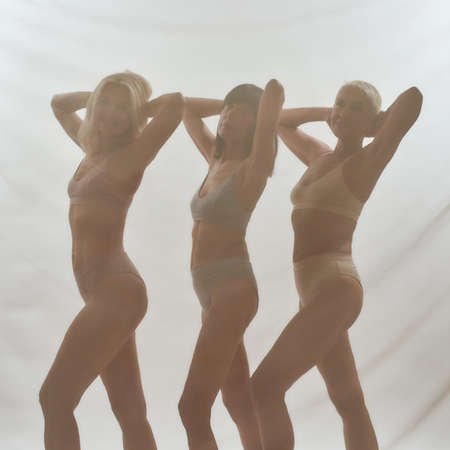 Energetic ladies throwing hands behind their headsの写真素材