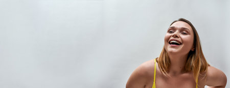Portrait of cheerful young woman wearing yellow bra posing isolated over grey backgroundの写真素材