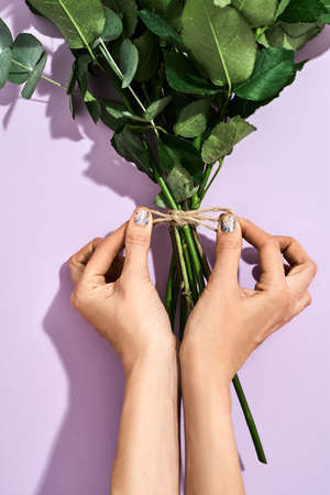 Top view of a female florist making beautiful bouquet for 8 March and International Womens day on purple backgroundの写真素材