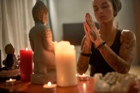 Praying young woman in front of altar with candlesの写真素材