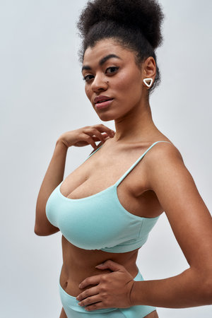 Portrait of sexy young mixed race woman wearing blue underwear looking at camera, posing isolated over light backgroundの写真素材