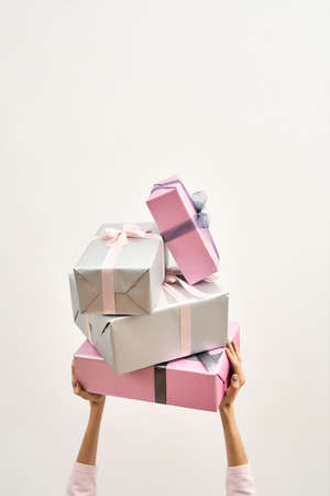 Sales and discount. Woman holding gift pile over the head against light background, vertical shotの写真素材