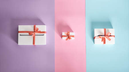 Presents for all family. Set of white gift boxes of different sizes with red bows on multicolor backgroundの写真素材