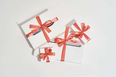 Top view of a pile of gift boxes of different sizes with red bows on white background