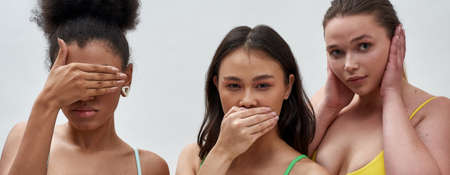 Cropped portrait of young beautiful diverse women covering mouth, eyes or ears with hands, posing isolated over light backgroundの写真素材