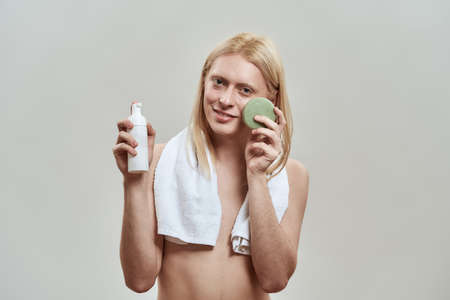 Happy young caucasian guy using facial sponge and foamの写真素材