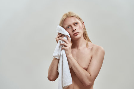 Shirtless young caucasian man wiping his face using towelの写真素材