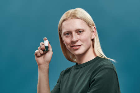 Young guy with manicured hands holding nail polish bottle