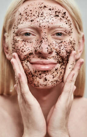 Portrait of happy man applying scrub on his faceの写真素材