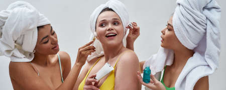 Portrait of cute diverse young women wearing colorful underwear and head towel having fun, trying...
