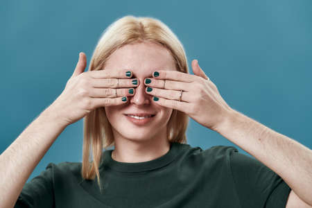 Portrait of young man putting manicured hands on eyesの写真素材