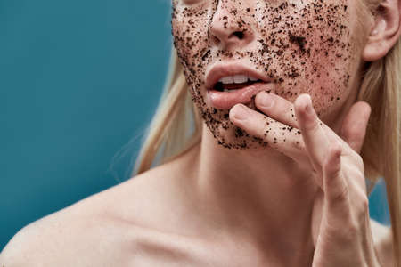 Young caucasian blond man peeling his face with scrubの写真素材