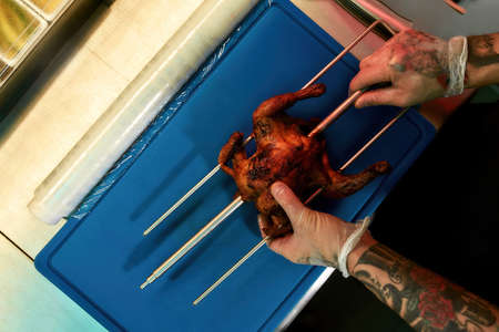 Professional chef taking off chicken from grillの写真素材