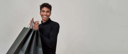 Happy young african american man with shopping bagsの写真素材