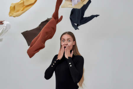 Surprised young caucasian woman under flying clothesの写真素材