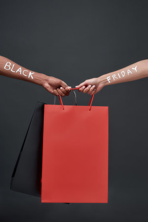 Hands of with Black Friday lettering holding paper bagsの写真素材