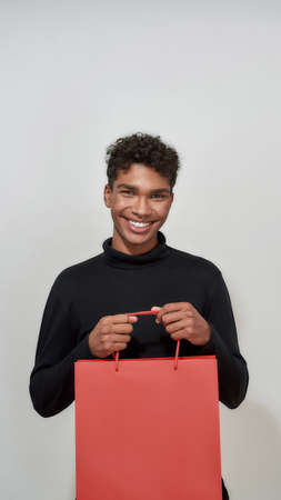 Happy african american boy holding red paper packet