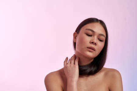 Young gorgeous asian woman touching her healthy and strong long hair and looking downの写真素材
