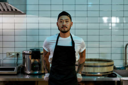 Asian chef standing in the kitchen in an apronの写真素材