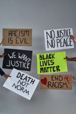 Placards with anti racist sayings on light background