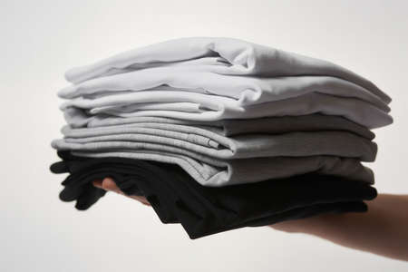 Stack of multi colored shirts on male handの写真素材