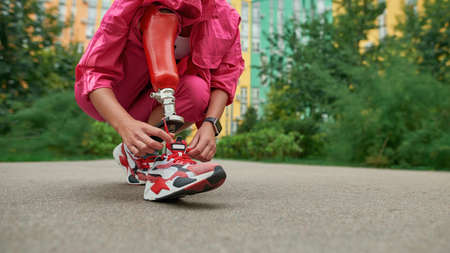 Disabled person with prosthetic leg tying shoelace
