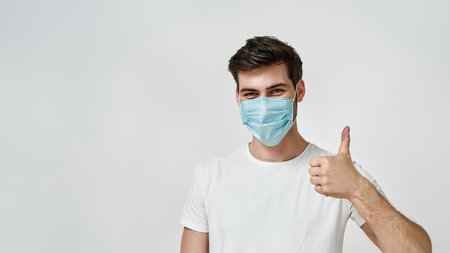 Man wearing medical mask showing the thumbs up