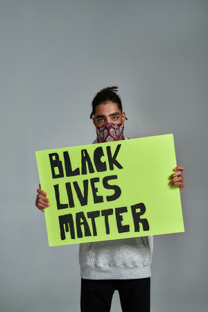 Young gypsy man holding placard with anti racism quoteの写真素材