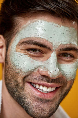 Young man with green mask applied on his faceの写真素材