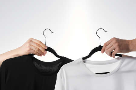 Basic wear. Hand holding black t-shirt on a hanger against white backgroundの写真素材