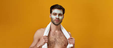 Man with naked torso with creamy mask on his faceの写真素材