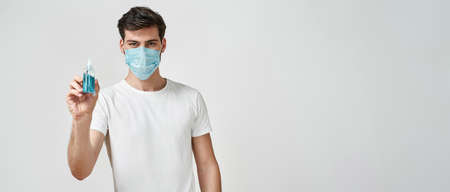 Man in medical mask holding hand sanitizer gelの写真素材