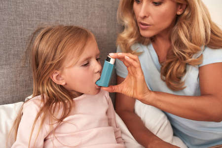 Portrait of a mother curing her daughters asthma attack