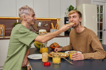 Happy homosexual pair feeding each other during dateの写真素材