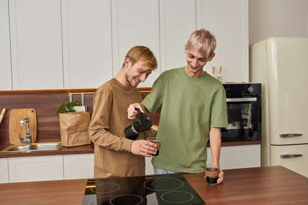 Happy young caucasian gay couple pouring coffee