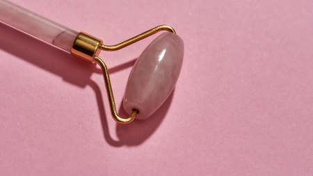 Closeup of Rose quartz facial massage roller isolated over pink backgroundの写真素材