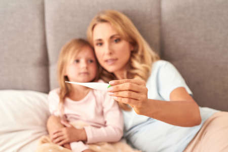 A picture of a mother checking her daughters temperature