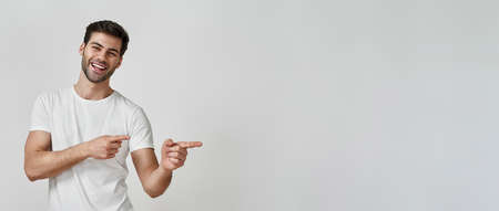 Man wearing t-shirt pointing fingers to the sideの写真素材