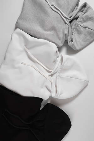 Cropped shot of three perfectly folded monochrome sweatshirts gray, black and white laid out in a row isolated over white backgroundの写真素材