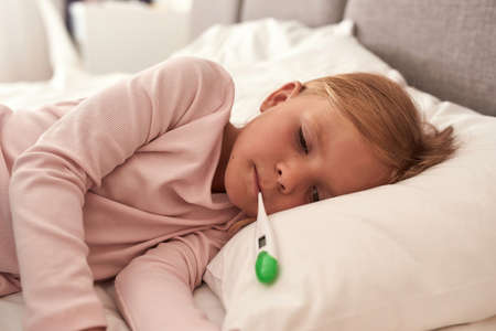 A picture of a girl lying in the bad with high fever croppedの写真素材
